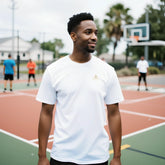 Premium Unisex Crewneck T-shirt | Cavaliére in white with gold embroidered logo, worn outdoors on basketball court